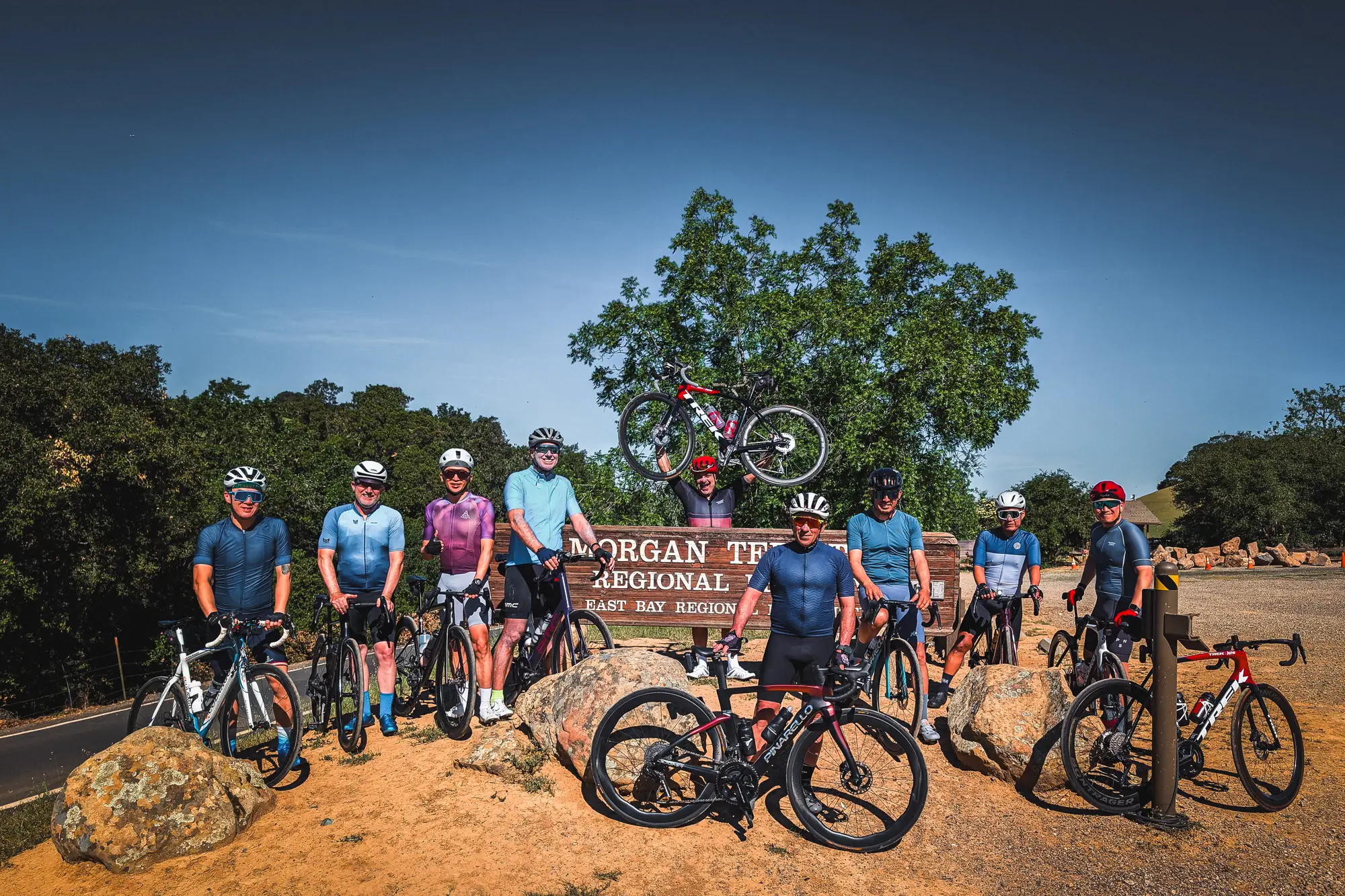 Ten Connected Cyclist riders with their road bikes in front of the Morgan Territory Regional Preserve sign