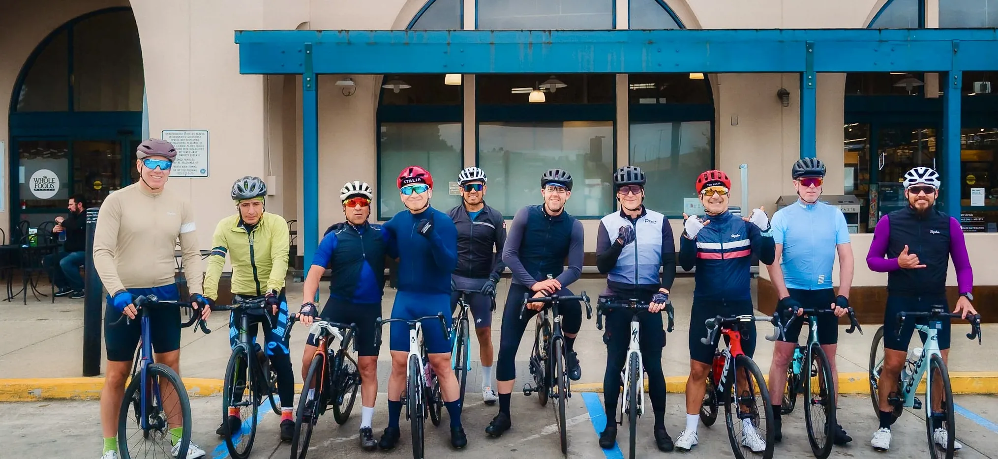 Ten cyclists lined up with their bikes outside Whole Foods before a Saturday group ride